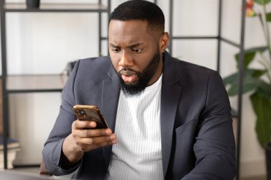 Genç Afro-Amerikan akıllı telefondan beklenmedik kötü haberler okuyor.