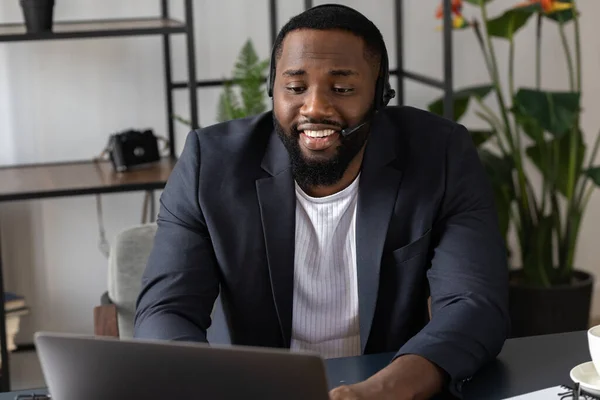 Happy millennial african american businessman in headphones with headset holding video call with clients partners