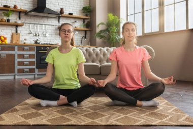 Nilüfer pozisyonunda iki genç mutfakta meditasyon yapıyor.
