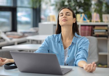 Yakışıklı başarılı iş adamı, ofiste otururken meditasyon yapıyor.