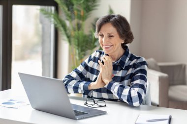 Mutlu gülümseyen beyaz kadın online eğitim kursuna gidiyor ya da merkez ofisten bilgisayarla bilgisayar başında sohbet ediyor.