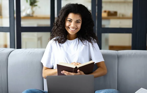 年轻的非洲裔美国女孩坐在家里的沙发上 用笔记本电脑上网学习 — 图库照片