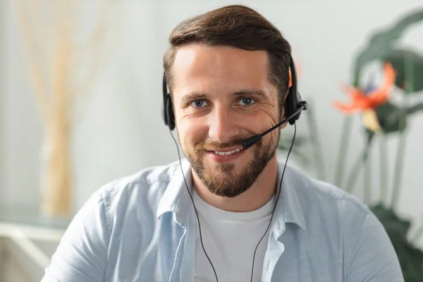 Portrait of smiling caucasian man support service operator in headset wireless headphones with microphone looking at the camera, satisfied worker concept