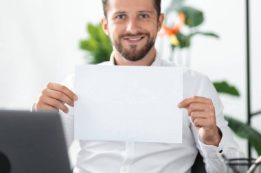 Kafkasyalı genç bir iş adamı, elinde senin mesajın için yeri olan boş bir kağıt tutuyor. Elinde boş bir kağıt parçasıyla, başarılı bir gülümseme temsilcisi. Banka kredisi, işe alım...