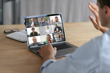 Çevrimiçi toplantı, grup beyin fırtınası kavramı. Başarılı bir adam bilgisayar ekranında elini sallıyor, video konferansı sırasında çalışanları selamlıyor.