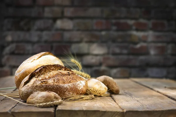 Bakery background. Set of freshly baked crispy bread and buns with ears of wheat on a wooden table in a bakery. copy space