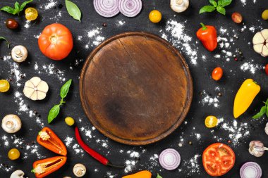 Siyah taş arka planda İtalyan ev yapımı pizza pişirmek için malzemelerle dolu yuvarlak vintage kesim tahtası.