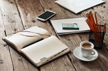 blank notebook on wooden table with a cup of black coffee