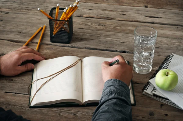 Mão de homem escrevendo algo em caderno em branco — Fotografia de Stock