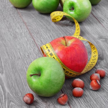 ripe apples lie on a wooden table in a tape to measure