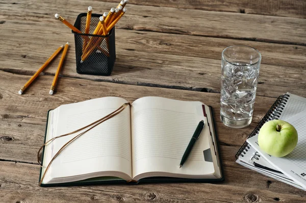 Diario en blanco en la mesa de madera con un vaso de agua, manzana y lápiz de primer plano —  Fotos de Stock