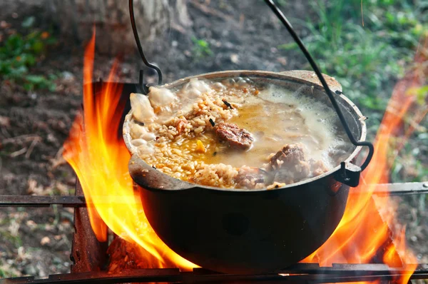 Cooking pilaf in a casserole on the fire close up — Stock fotografie