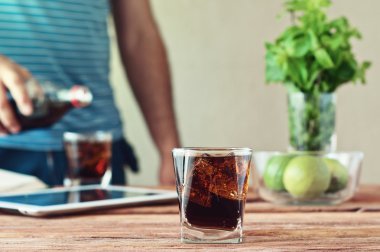 Full glass of cola in the foreground on wooden table closeup clipart