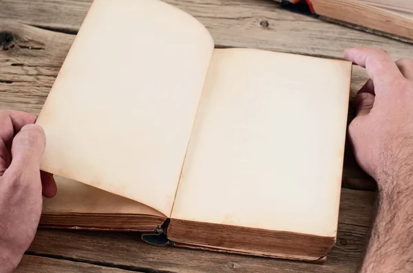 Men turns the page of the book on the wooden table — ストック写真