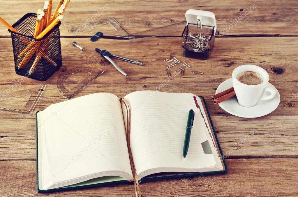 open notebook with blank pages on wooden desk with a cup of coff