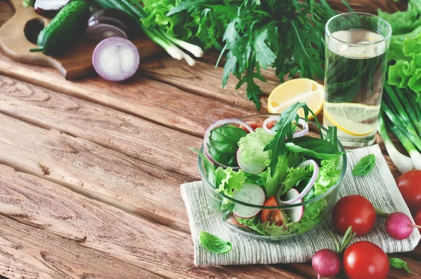 Salade de légumes avec un verre d'eau sur la table — Photo