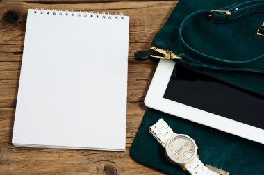 defter ile bir kadın çantası, tablet ve saatler