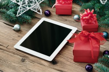 White tablet computer with Christmas present on wooden table clo