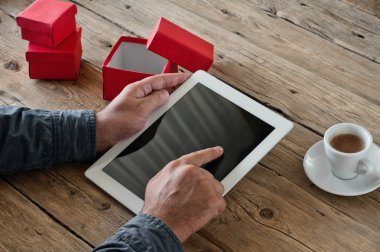 man orders Christmas gifts using a tablet computer