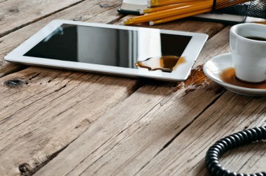 Spilled coffee on white tablet computer on the office table