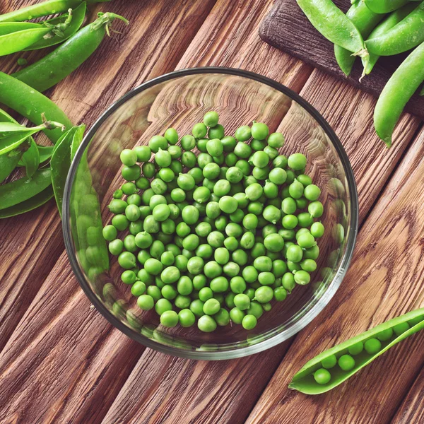 Green peas peeled in a glass bowl closeup — Stock Fotó