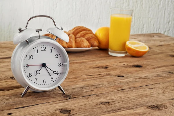 Reloj despertador redondo blanco sobre una mesa de madera — Foto de Stock