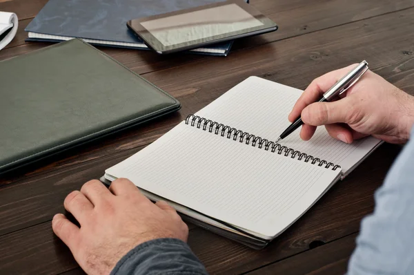 Mão de homem escrevendo algo em caderno em branco — Fotografia de Stock