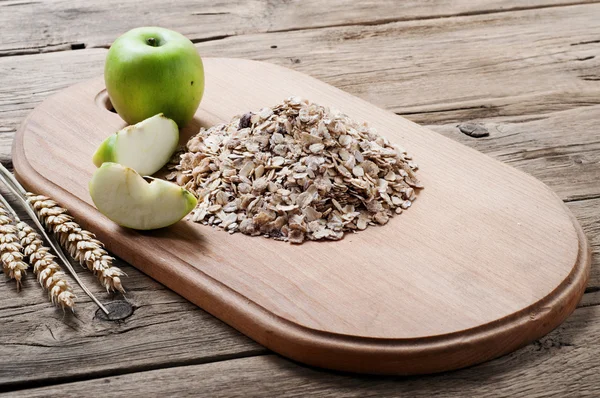 Handful of oatmeal on a wooden cutting board with apples — Stock Photo, Image