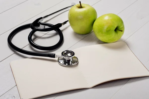Taccuino aperto con stetoscopio e mela — Foto Stock