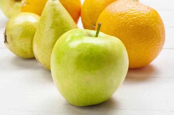 Крупный план спелое зеленое яблоко, апельсины с грушами — стоковое фото