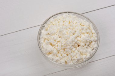 Cottage cheese in bowl on white a wooden surface