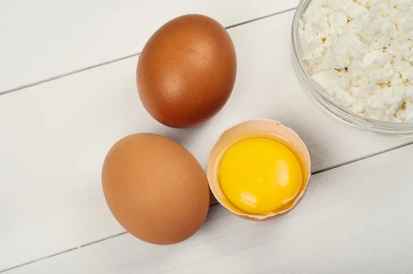 Whole and broken raw brown eggs with cottage cheese — Stockfoto