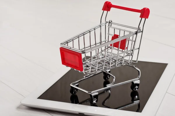 Nahaufnahme kleiner Einkaufswagen auf einem weißen Tablet-Computer — Stockfoto