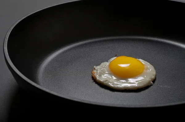 Жареные яйца в новой черной антипригарной сковороде — стоковое фото