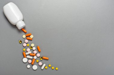 Pills and capsules spilling out of bottle clipart