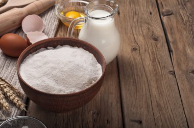 Flour, egg, milk on wooden table rustic kitchen