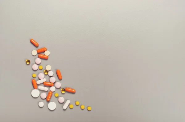 Spilling pills and capsules on a gray background — Stock Photo, Image