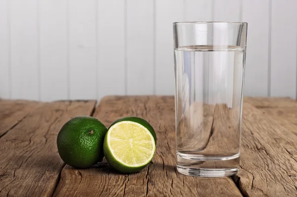 Glass of water with lime on a wooden table — Stock Photo, Image