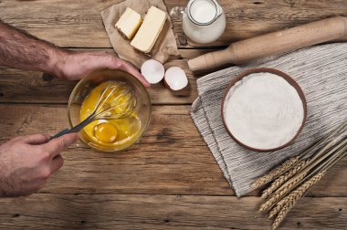 Male chef whipping eggs in the bakery on wooden table