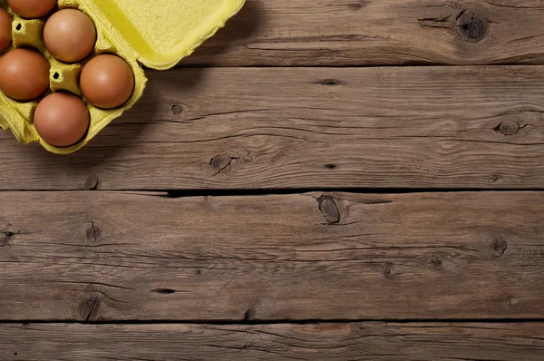 Huevos marrones en un barco amarillo sobre fondo de madera —  Fotos de Stock