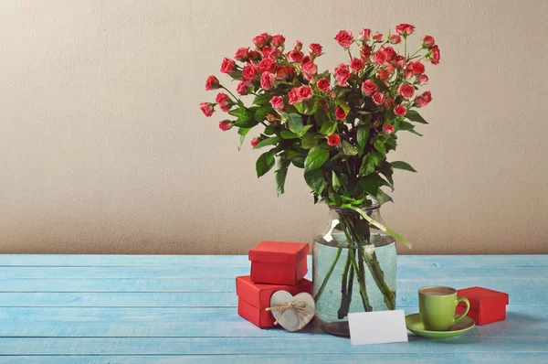 Buquê de rosas, presentes, xícara de café e cartão — Fotografia de Stock