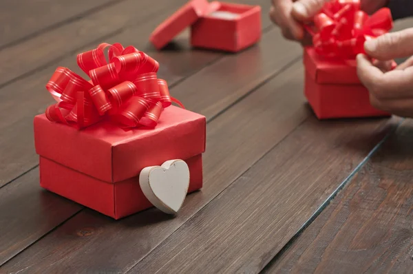 Caixa de presente vermelho com um arco vermelho na mesa de madeira — Fotografia de Stock