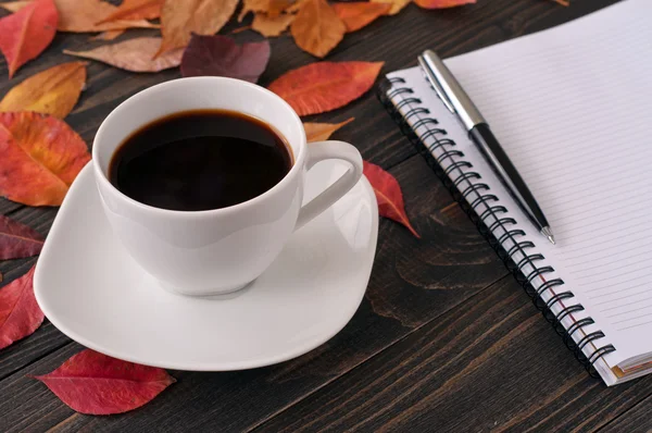 Amerikaanse kopje koffie met herfst bladeren, notebook en pen — Stockfoto