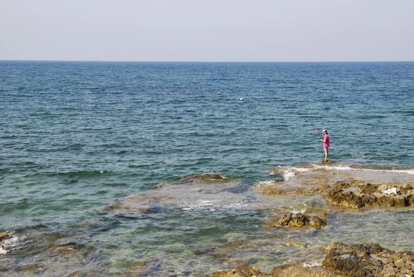 Fisherman standing on the rocky shore of the Mediterranean — Stock Photo, Image