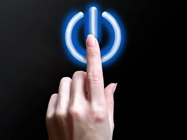 Aynalı siyah arkaplandaki mavi fünyeli güç düğmesi. Parmağını güç düğmesine basıyorsun.