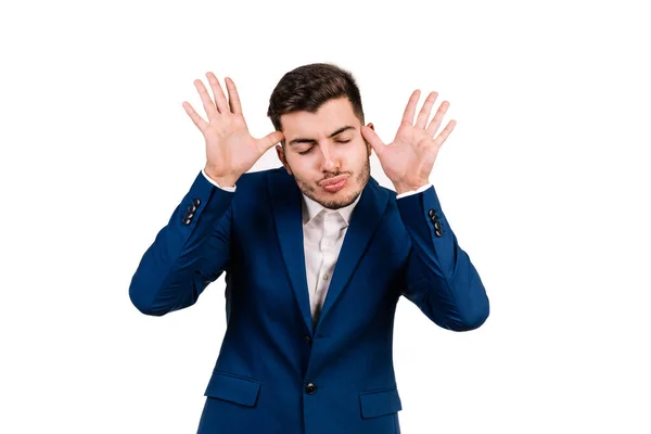 Beyaz arka planda, esmer saçlı, elleri ve yüzüyle komik bir ifade takınan beyaz tenli bir iş adamının portresi.