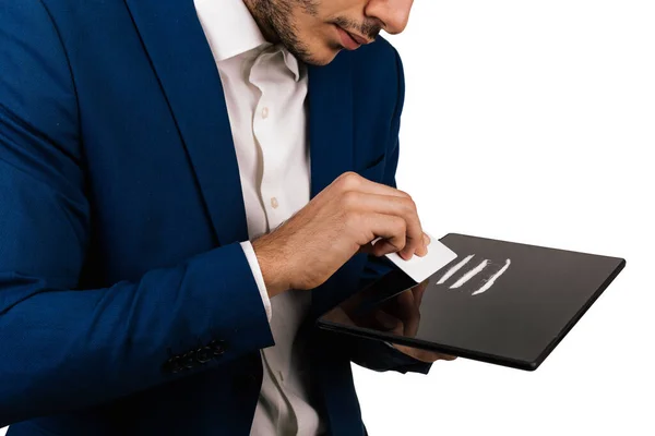 Takım elbiseli genç bir adamın tablet üzerinde kokain hazırlarken yakın çekimi. Ağır ilaçlar.
