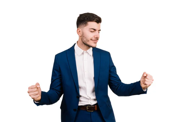 Zarif bir takım elbise giymiş genç bir işadamı beyaz bir arka planda kolları ve yüzü izole bir şekilde kazananın ifadesini takınıyor.