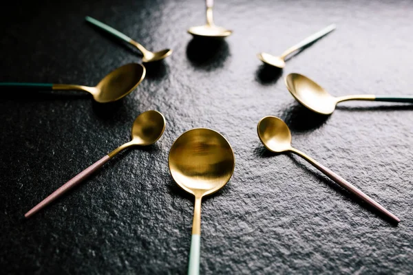 Siyah arkaplanda daire şeklinde dizilmiş şık ve renkli kaşıklar