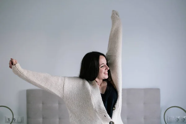 Kahverengi saçlı, çilli, yatakta esneyen beyaz kadın, hırka ve siyah iç çamaşırı giyiyor.